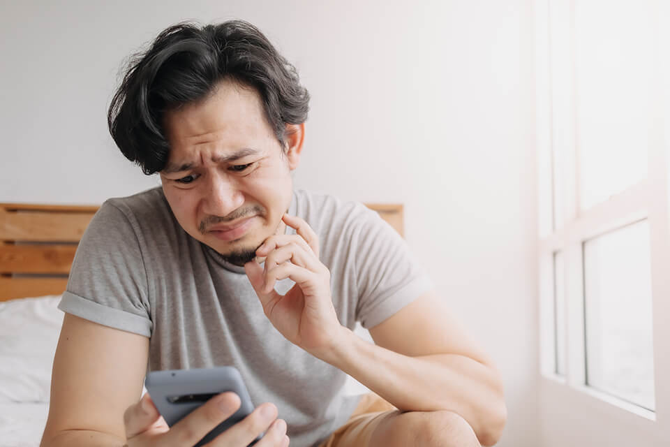 スマホ_見て_悩む_男