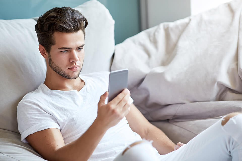 スマホを見る男_ベッド