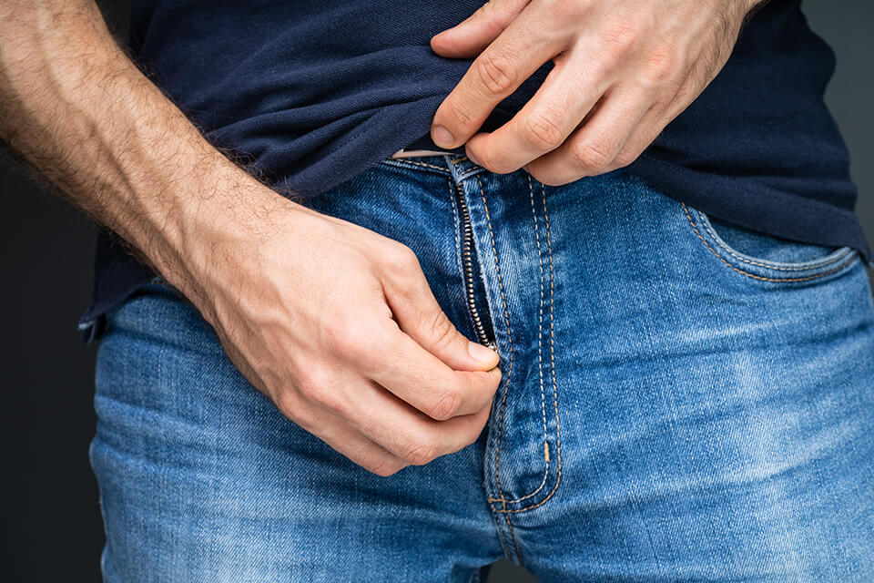 ズボンのチャックを下げる男