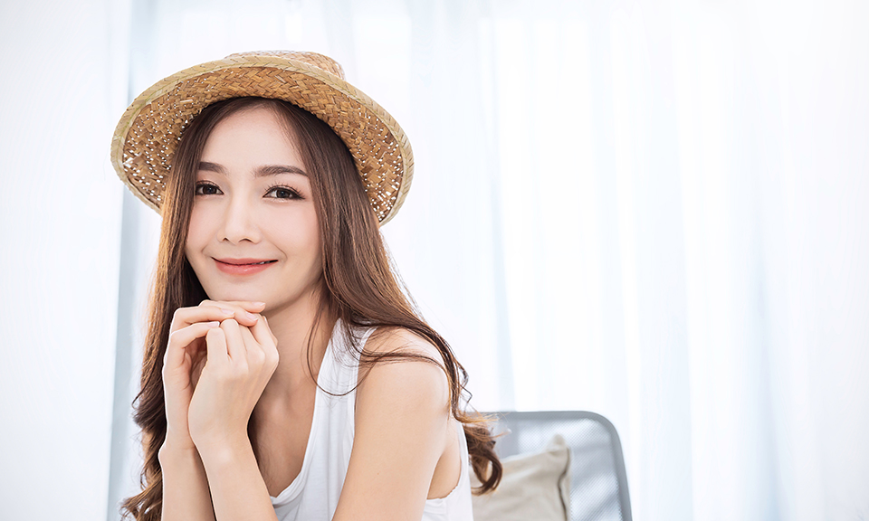 麦わら帽子をかぶって微笑む女