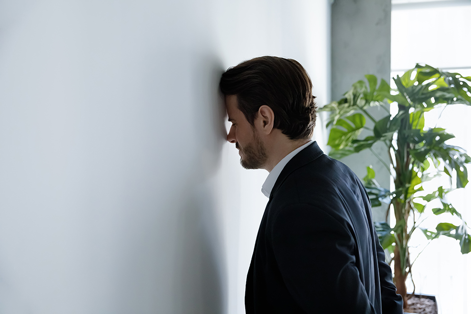 男_頭を壁につける_スーツ_会社